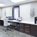 elegant front desk area with monitors, a window, dark wood cabinets, and a printer