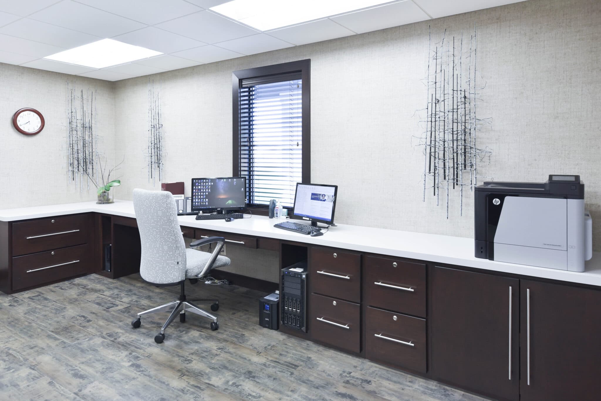 elegant front desk area with monitors, a window, dark wood cabinets, and a printer