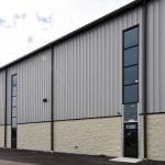 exterior wall of pre-engineered metal building with tall windows and metal siding