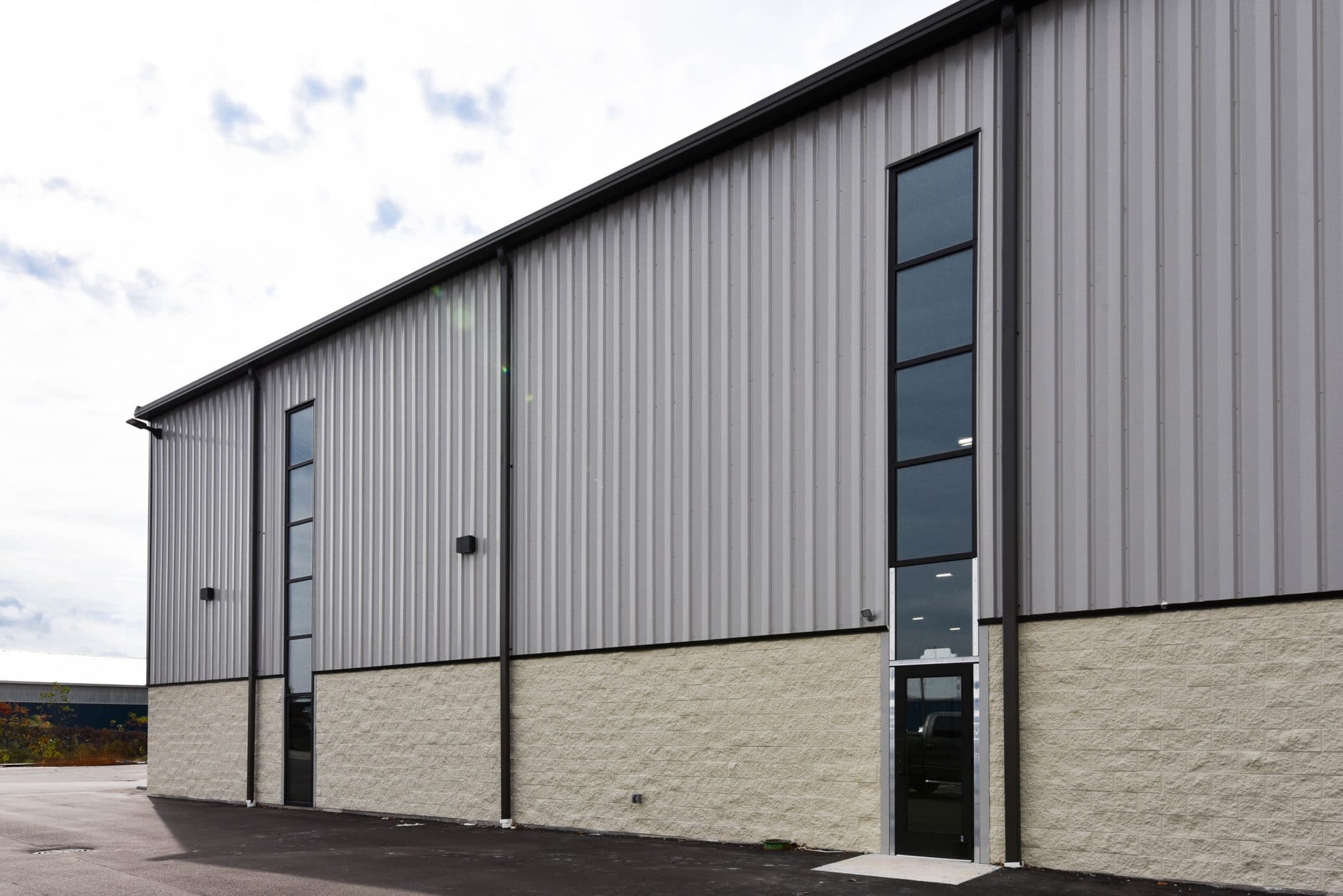 exterior wall of pre-engineered metal building with tall windows and metal siding