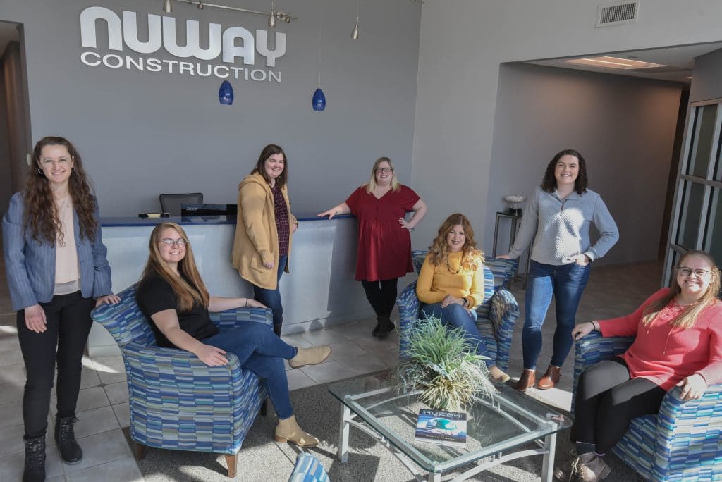 group of women who work at Nuway Construction posing cheerfully in lobby