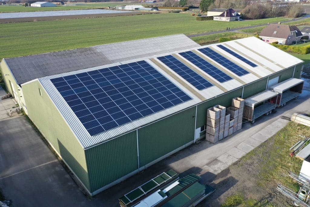green paneled industrial building with solar panels on roof