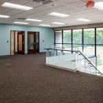 office landing with turquoise walls, large windows, and glass staircase railing