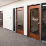 carpeted office hallway with wooden and glass doors