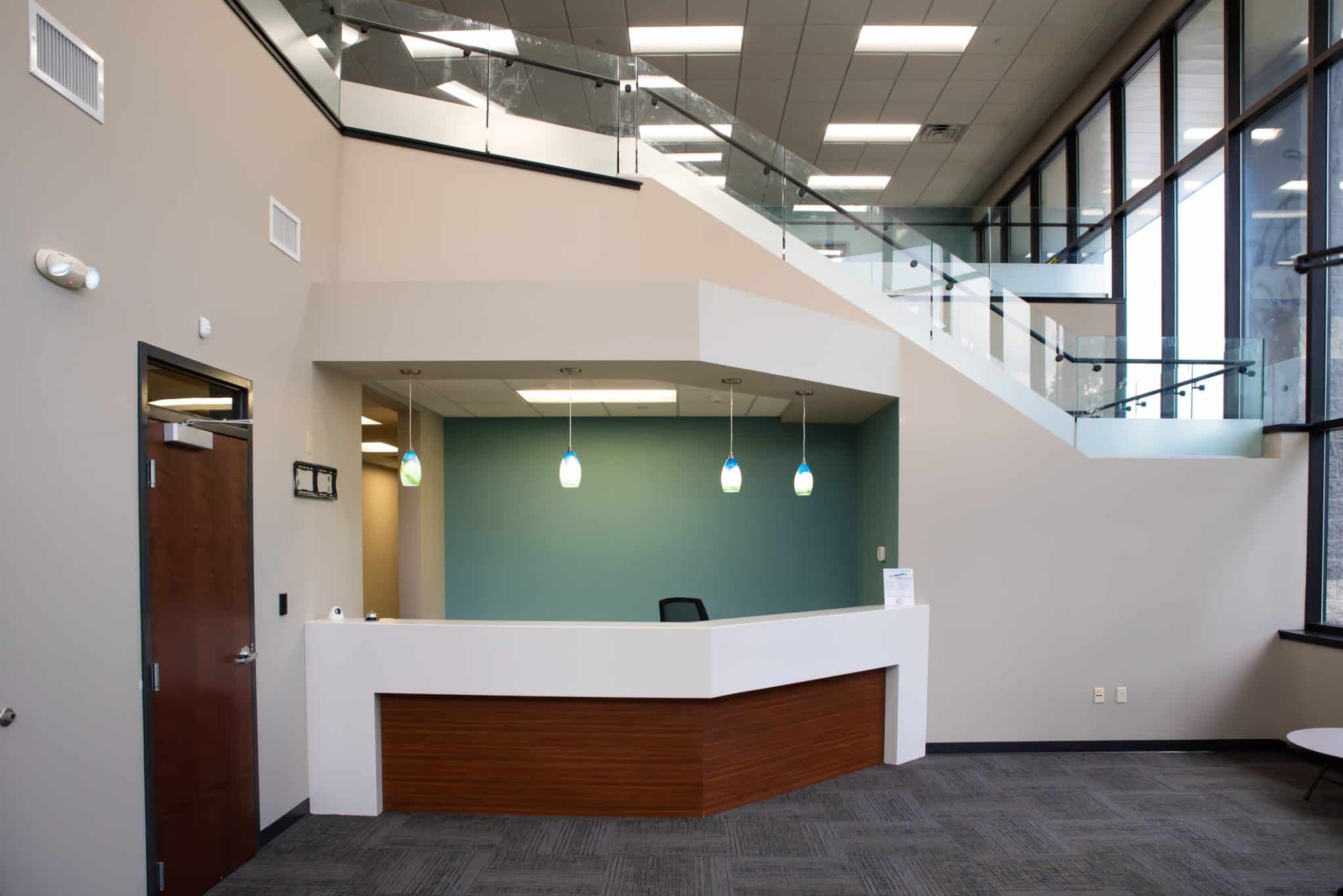 office lobby with beige walls and glass staircase railing