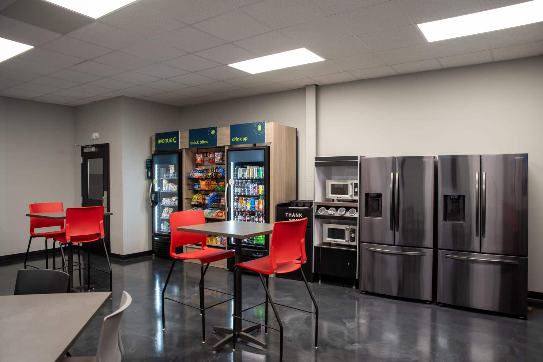 employee break room with fridges, high top tables and chairs, and vending machines
