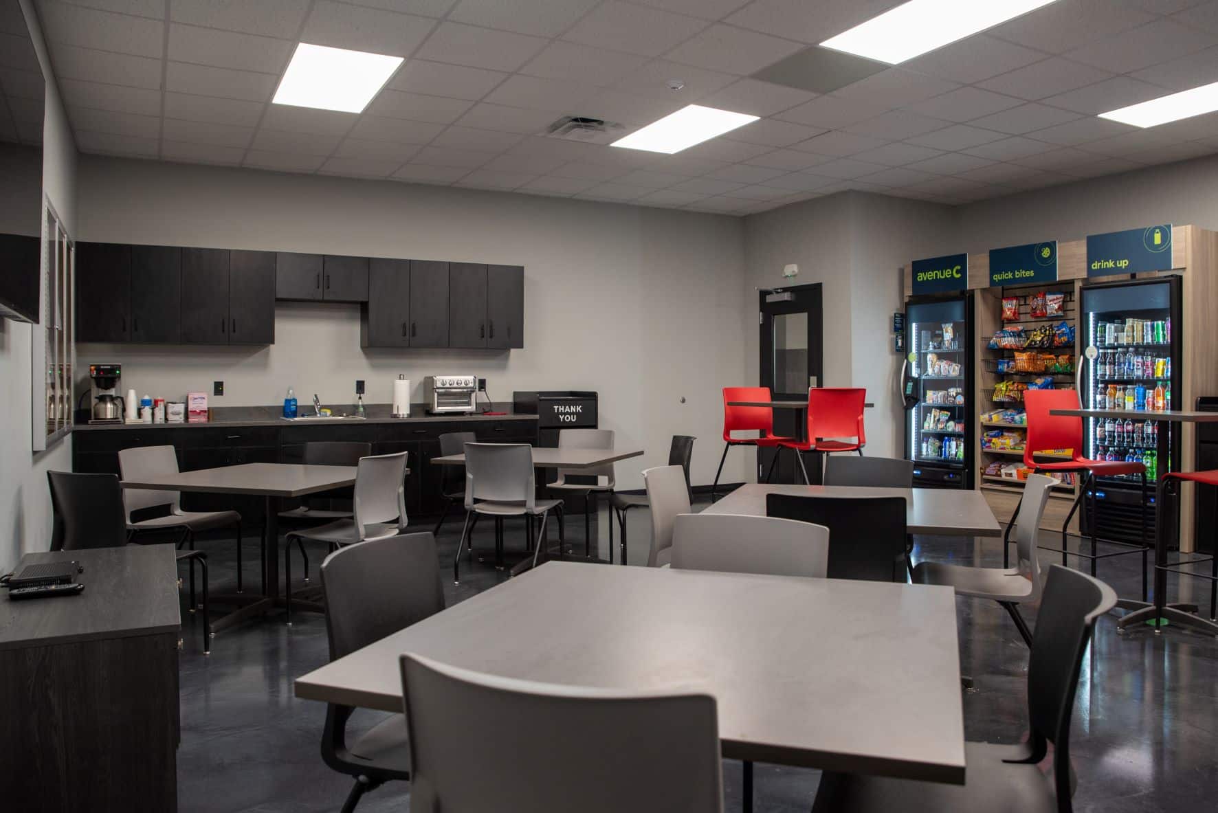 employee break room with kitchenette, tables and chairs, and vending machines