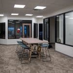 small conference table and chairs in open area between glass walled offices