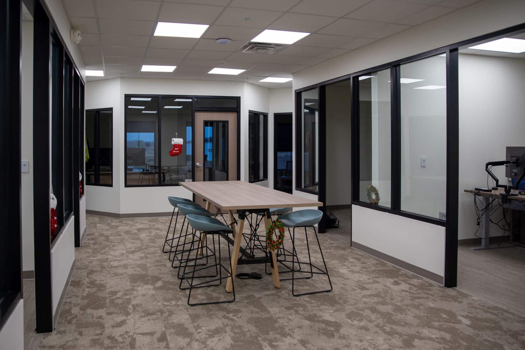 small conference table and chairs in open area between glass walled offices