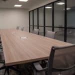 empty conference room with long table, chairs, and glass wall