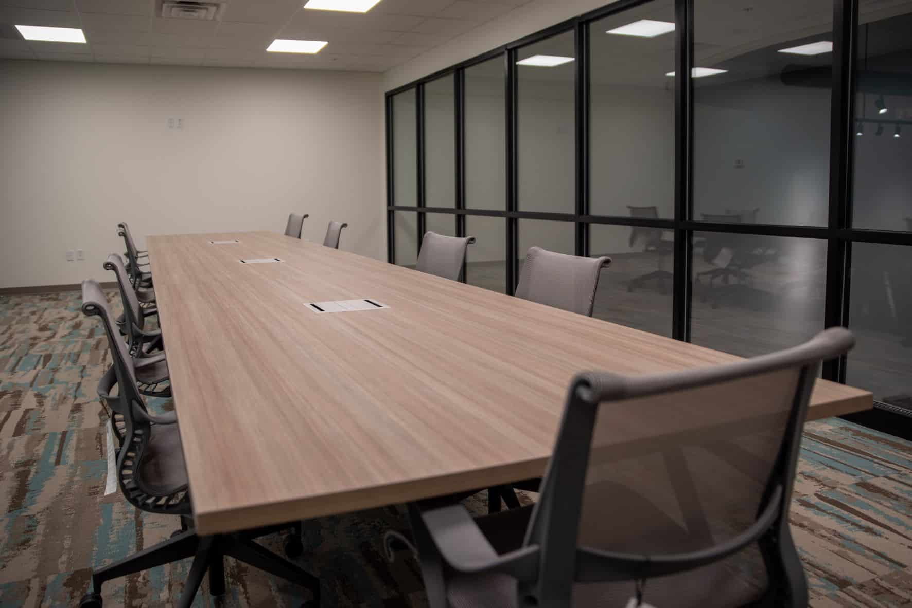 empty conference room with long table, chairs, and glass wall