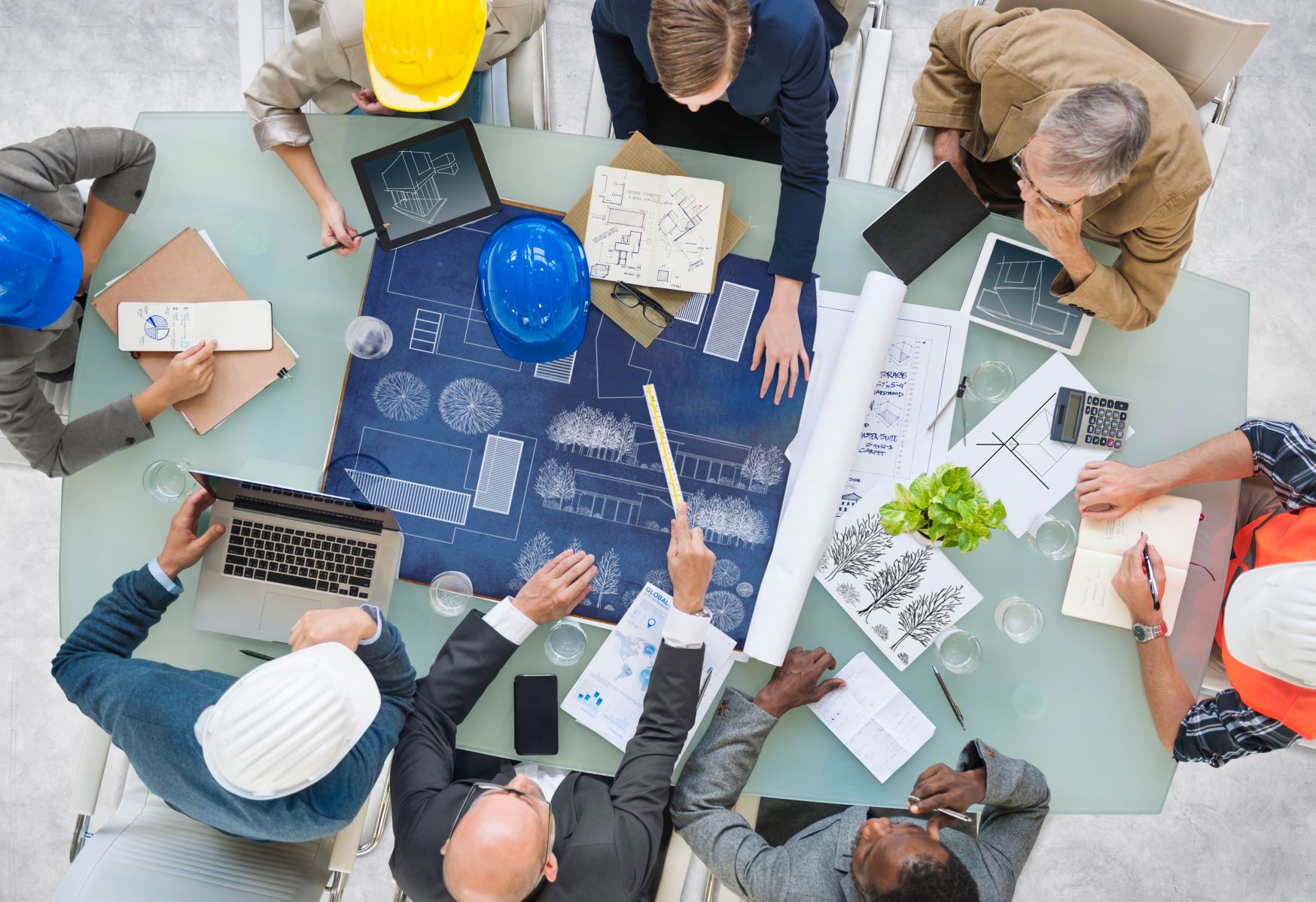 group of professionals at a conference table looking at blueprints