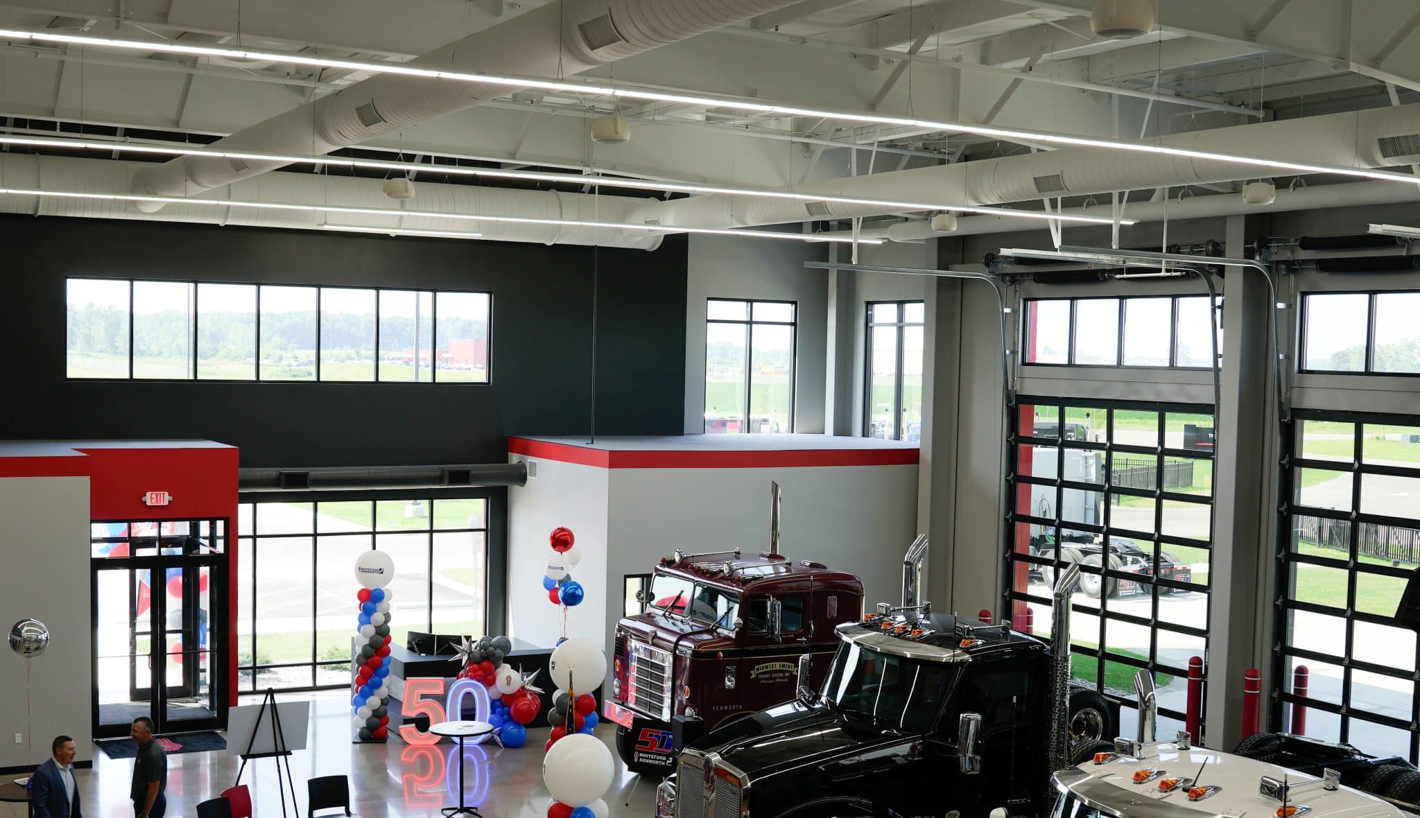 Interior of Whiteford Kenworth Toledo showroom with large windows, trucks on display, and 50th anniversary decorations.