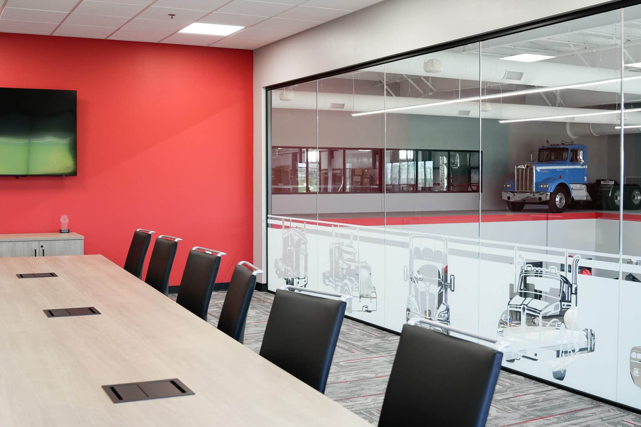 Conference room at Whiteford Kenworth Toledo with long meeting table, black chairs, and red accent wall.