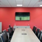 Boardroom at Whiteford Kenworth Toledo featuring red wall, mounted TV, and modern meeting table with chairs.