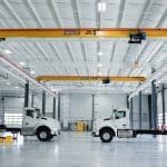 Truck service area at Whiteford Kenworth Toledo with two white Kenworth trucks and overhead cranes for lifting.