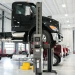 Black Kenworth truck lifted on hydraulic system inside Whiteford Kenworth Toledo service bay.