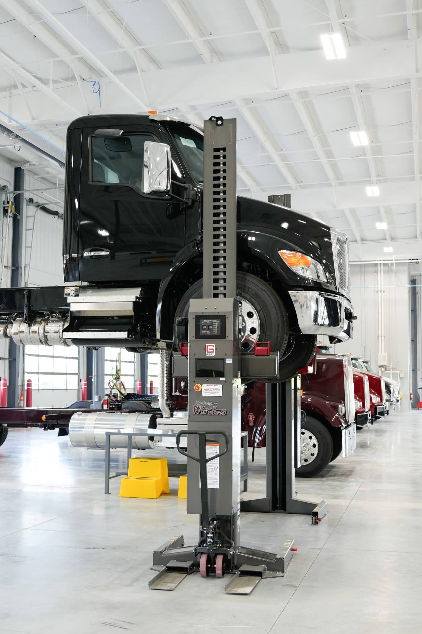 Black Kenworth truck lifted on hydraulic system inside Whiteford Kenworth Toledo service bay.